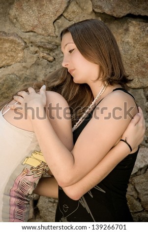 Teenage girl comforting crying friend with warm hug