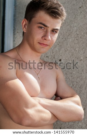 Happy young stylish man hands crossed on naked torso looking in camera outdoors