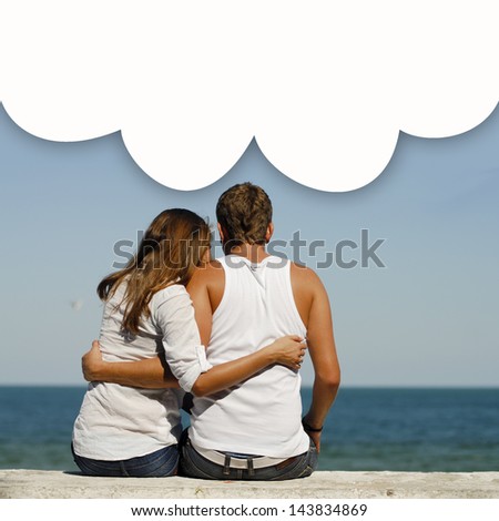 Young happy couple at sea coast sitting hugging dialogue box above them