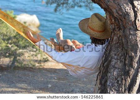 Lazy time. Man in hat in a hammock on pine tree in Crimea a summer day