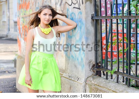 Young beautiful stylish woman standing at graffiti wall street fashion on the summer outdoors background