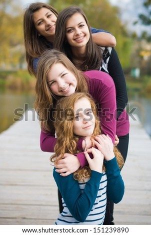Four happy teenage girls friends outdoors smiling portrait