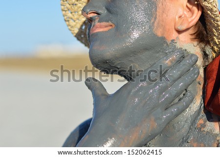 Mature woman applying mud on face and hands outdoors