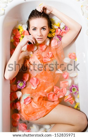 Beautiful sexy young woman in bath with flower petals view from above