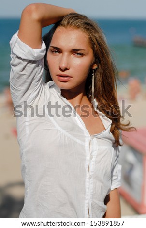 Spontaneous beautiful relaxing woman by sea side looking at camera in summer outdoors