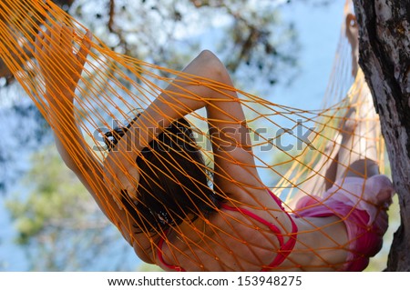 view of nice smooth woman back lying in summer outdoors hammock on blue seacoast background