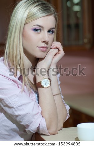 sensual blond girl with hair style holding a cup of coffee or tea looking at camera
