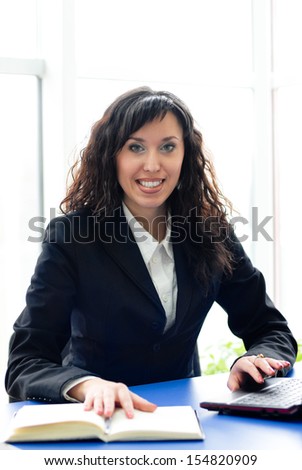 Successful woman at office workplace with mobile cell phone happy smiling & looking at camera
