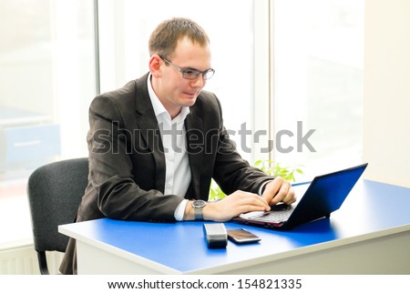 Businessman using laptop in office & happy smiling