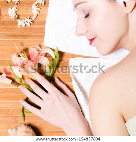 Beautiful lady face happy smiling with flower & perfect skin relaxing in spa salon