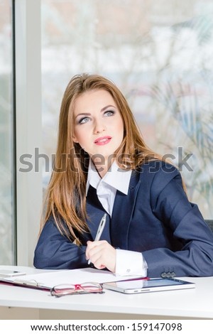 Businesswoman in man\'s suit signing with pen at her office fashion styled looking up