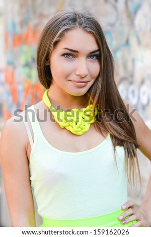 Young beautiful stylish woman happy smiling & looking at camera standing at graffiti wall street fashion