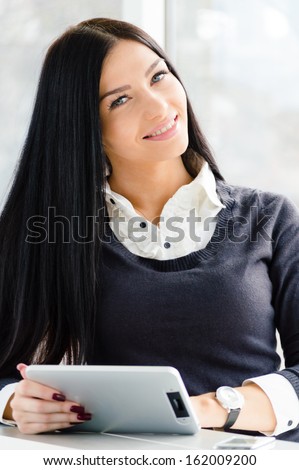 young pretty business woman happy smiling using tablet PC relaxed near window at her office