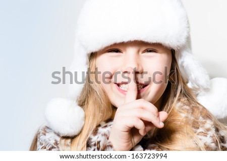 happy smiling & looking at camera little girl secrets in white winter hat