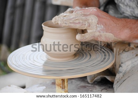 Handmade Craftsman making vase from fresh wet clay on pottery wheel hands closeup