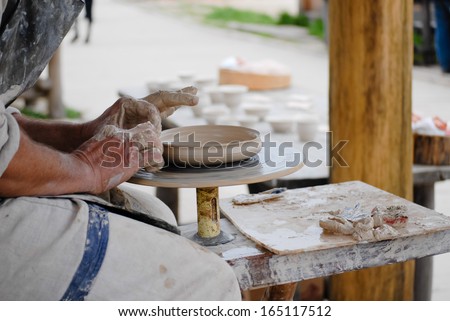 hand made craftsman making plate from fresh wet clay on pottery wheel hands closeup