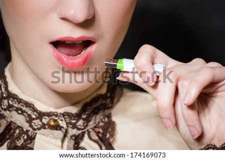 Woman plugging micro SD memory stick to her mouth closeup portrait