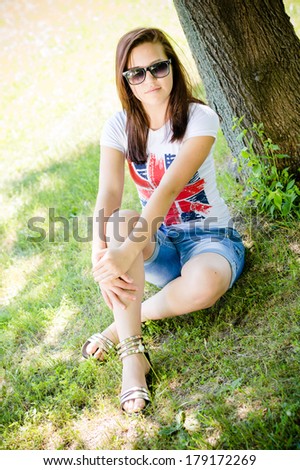 Happy young woman school teenage girl sitting at tree in park on summer day