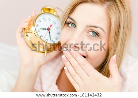 sweet cute charming young woman blond girl with sleepy face and an alarm clock in hand