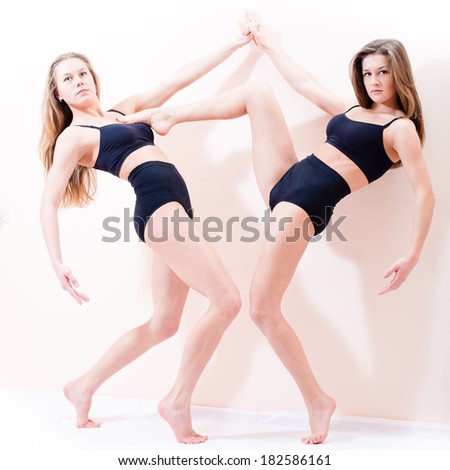 portrait of two sexy attractive young athletic figure woman beautiful blond girl friends standing on tiptoe and one of them set foot on the chest of another