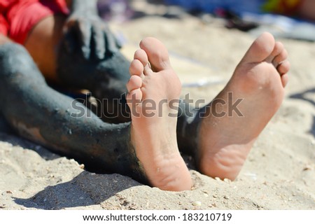Man applying mineral blue mud on knee on the outdoors summer background