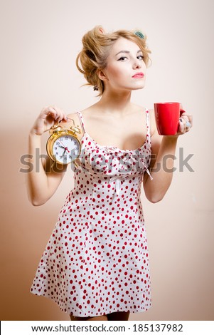 beautiful blond funny pinup green eyes woman with curlers holding alarm-clock & cup of hot drink looking at camera portrait