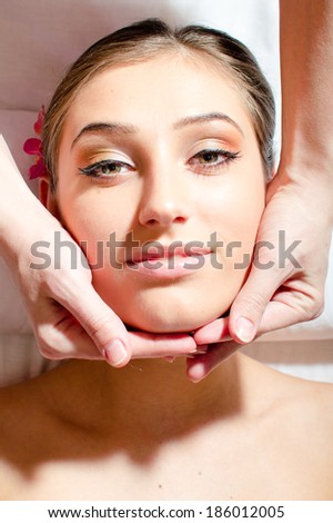 beautiful nice young woman on spa treatments during face massage, relaxing & looking at camera portrait