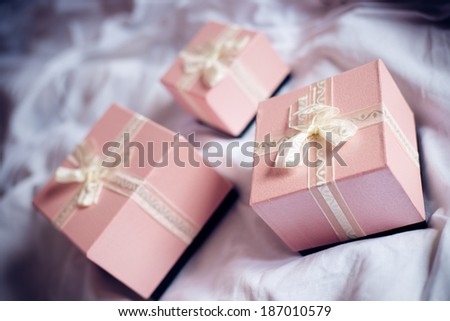 Three gorgeous beautiful luxury boxes pink presents with white ribbon on white bed background