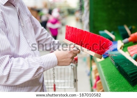 closeup on business man selecting or choosing and buying a sweeping broom for floor or path on the DIY department shopping store background