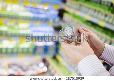 Energy efficient lighting choice: closeup on hands holding or selecting LED diode light bulb lamp in DIY department store