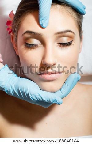 beautiful woman with orchid in her hair lying on massage table at spa getting massage closeup picture