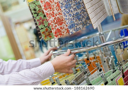 customer choosing or employee presenting colorful tiles in a supermarket or DIY department store
