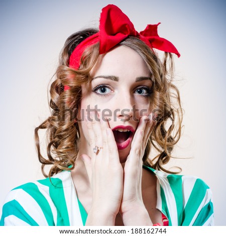 closeup portrait of beautiful elegant blonde woman with big blue eyes and red lips open mouth in surprise looking at camera on light blue background