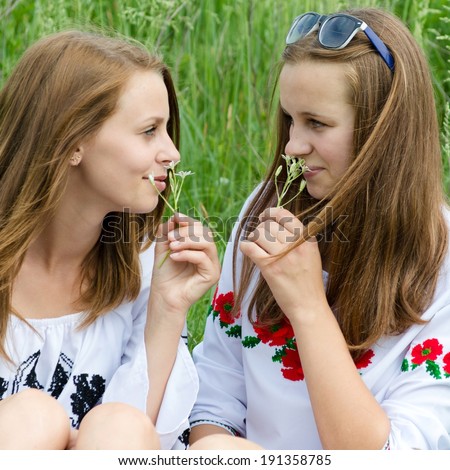 image of 2 smelling flowers beautiful young women teen girl friends having fun in spring or summer day outdoors background