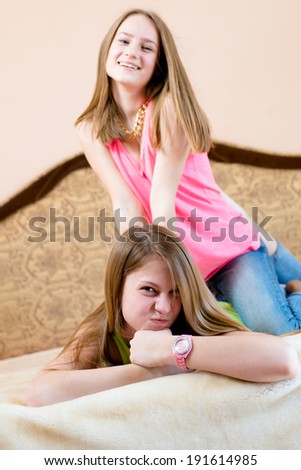 image of 2 best girl friends or sisters beautiful blond young women having fun playing in bed happy smiling & looking at camera portrait