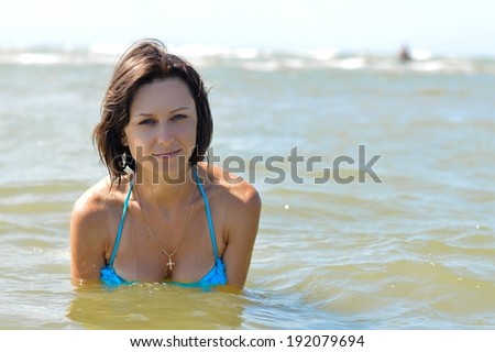 picture of young beautiful woman in blue bikini swimming in sea on summer day outdoors background