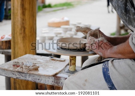 Image of closeup on craftsman hands making plate from fresh wet clay on pottery wheel