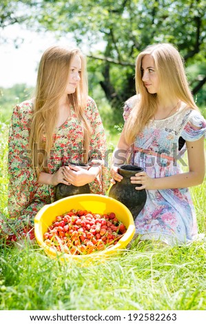 2 strawberry pickers: two happy young women teenage girl friends on farm gathering strawberry on bright summer day green outdoors background picture