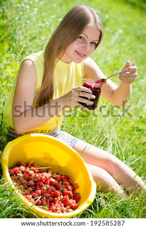 portrait of young pretty woman blond happy smiling teenage girl having fun eating strawberry jam on summer green outdoors background