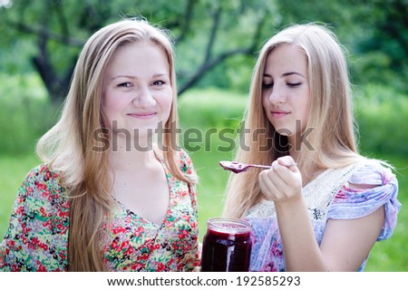 2 young pretty women happy teenage girl friends having fun eating strawberry jam on summer day green garden outdoors background closeup portrait