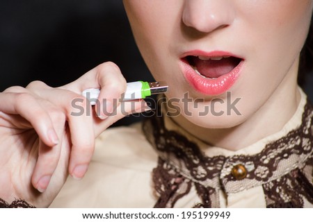 closeup image of woman plugging micro SD memory stick to her mouth closeup portrait concept