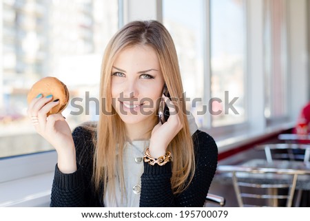 talking on mobile cell phone and having lunch happy smiling looking at camera beautiful young business woman cute blond girl having fun relaxing in restaurant or coffee shop close up portrait image