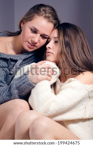 image of 2 beautiful blond & brunette girl friends friendly hugging in knitwear: she is my best friend who I can trust