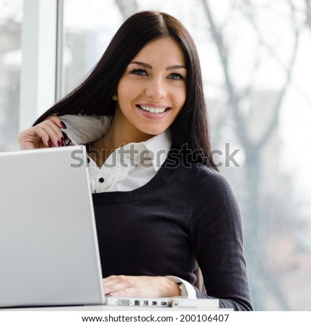 young business woman having fun using laptop PC computer at office desk happy smiling & looking at camera on light window copy space background portrait image