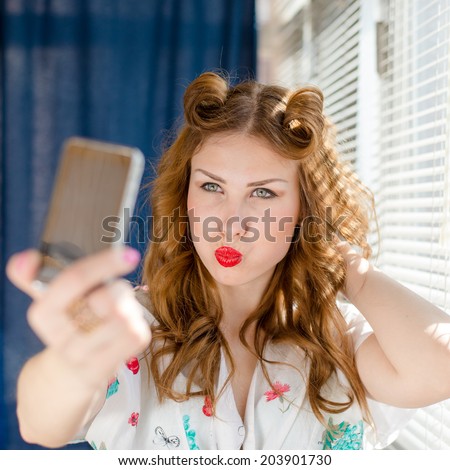 close up on taking funny selfie or selfy photo with smart phone beautiful young pinup lady having fun by window with white blinds over sun light rays copy space background portrait picture