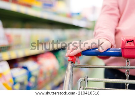 woman in a supermarket trolley carries, closeup on hand