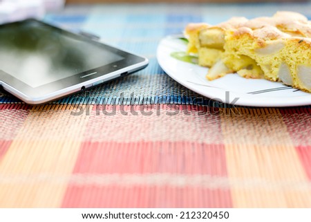 Piece of tasty biscuit apple pie and tablet pc on table together