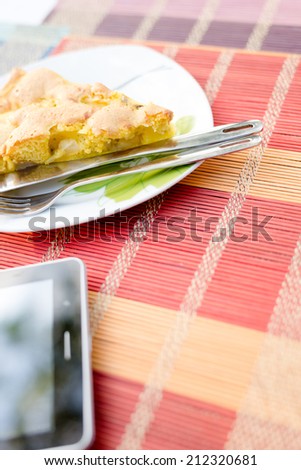 Piece of tasty biscuit apple pie and tablet pc on table together