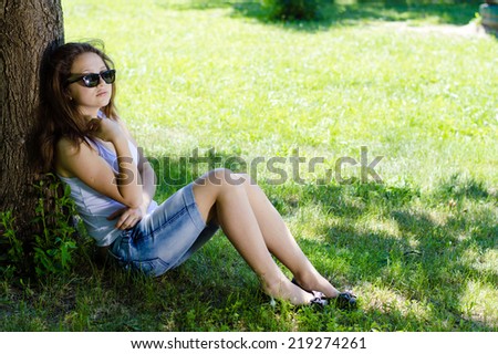 Happy young woman school girl sitting at tree in park on summer day