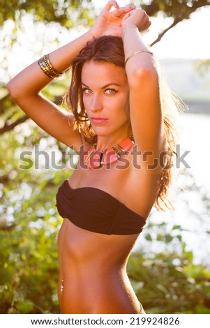 summer beauty: sexy young pretty lady having fun posing in bikini on water copy space background, warm tone